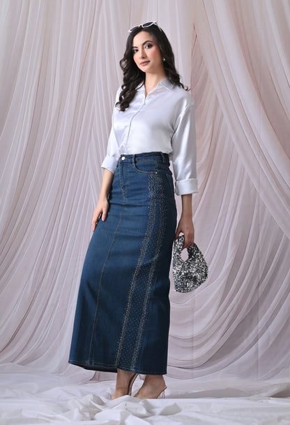 Woman wearing a white blouse and blue denim skirt against a white curtain background