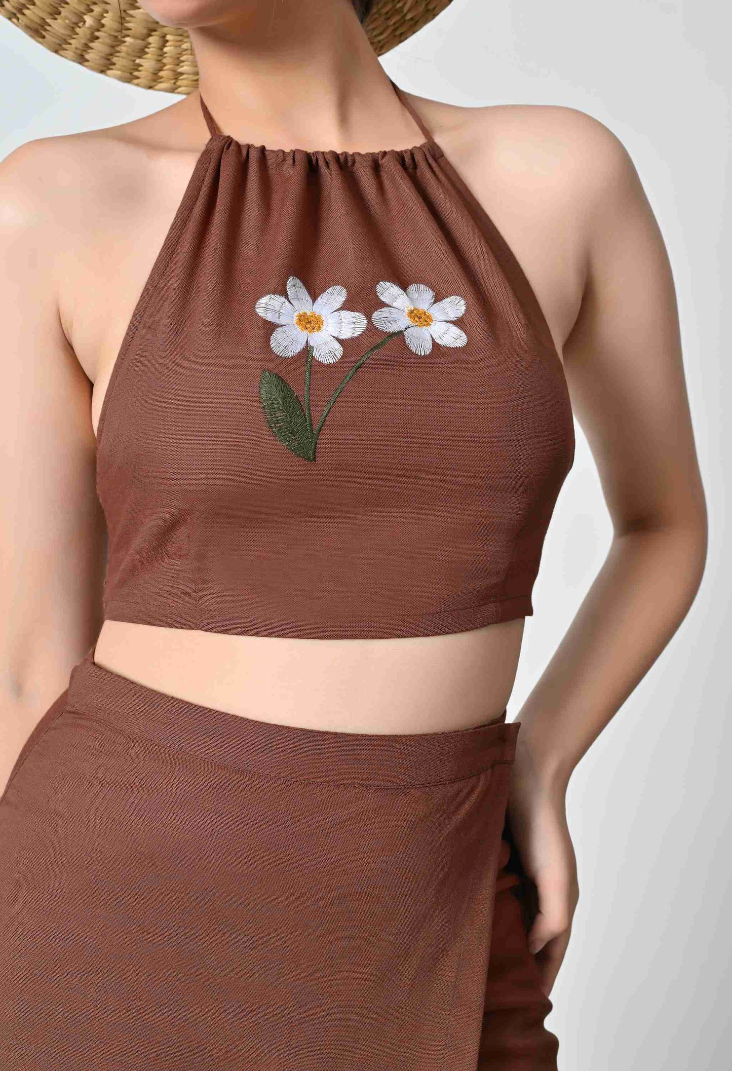 Brown halter top with floral embroidery on a plain background
