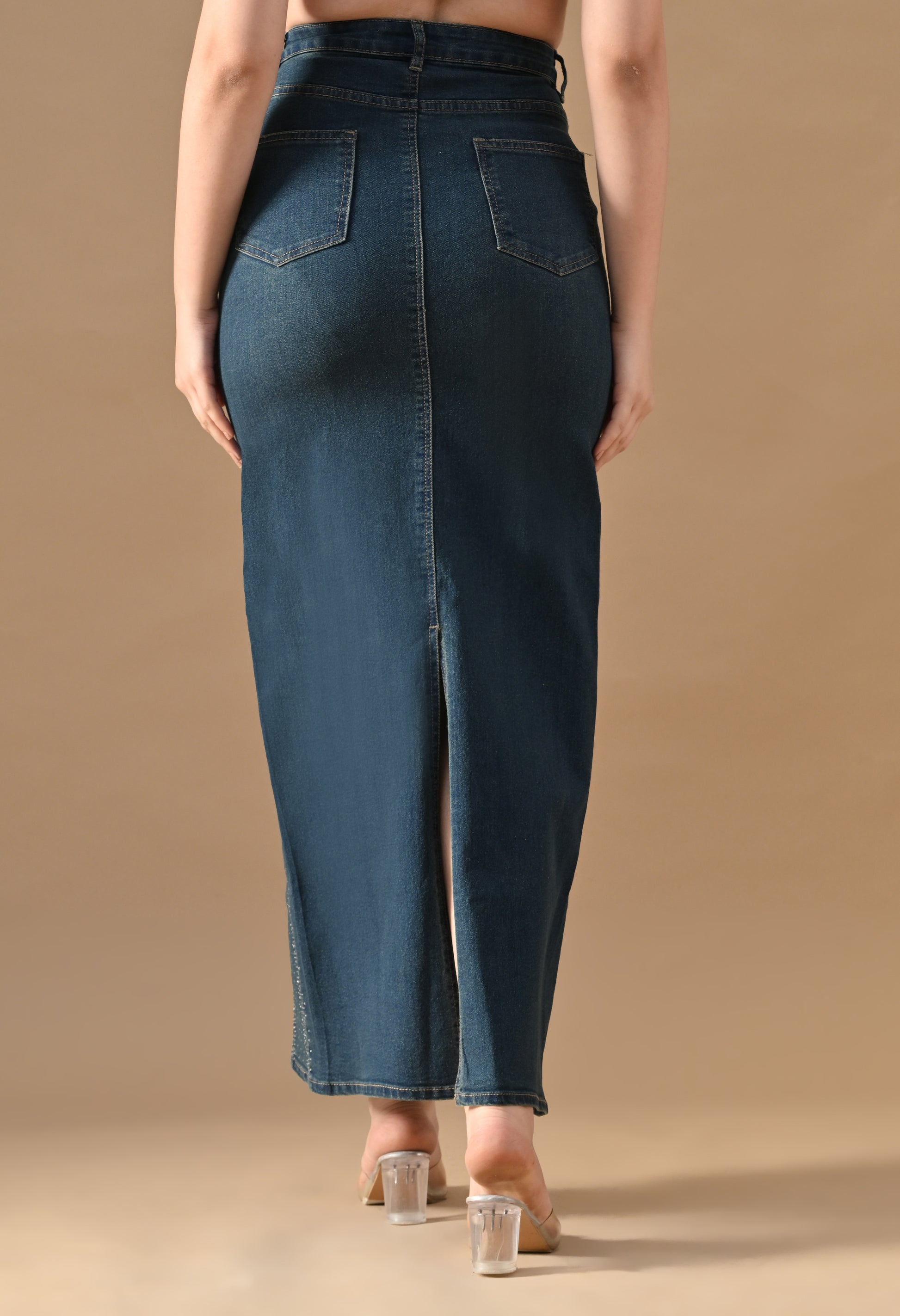 Long denim skirt worn by a person on a beige background