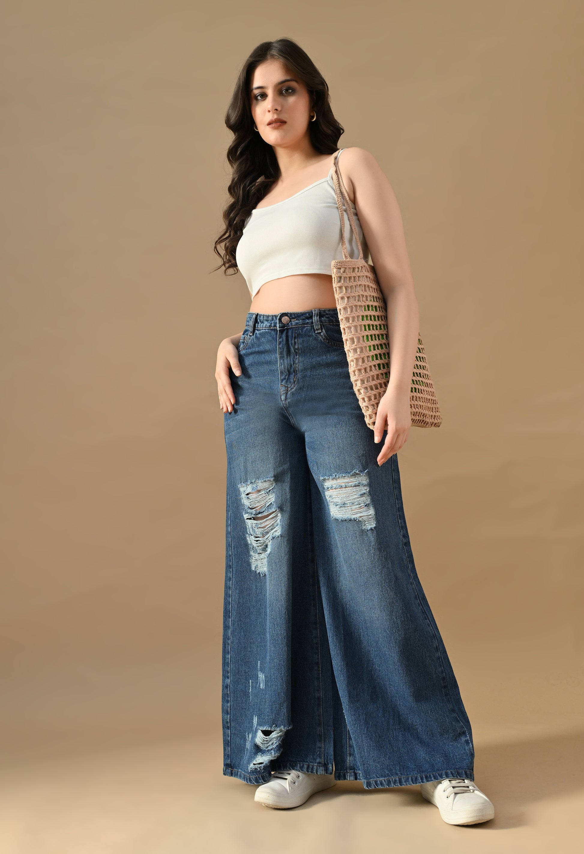 Woman wearing a white top and blue jeans with a beige background