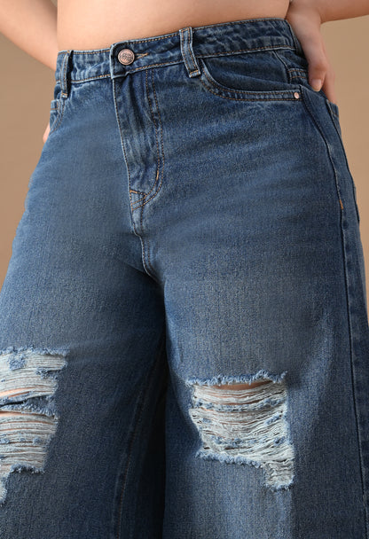 Close-up of distressed blue jeans on a beige background