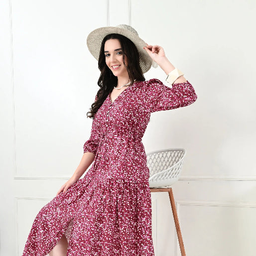 Woman wearing a floral dress and hat, sitting on a chair against a white background