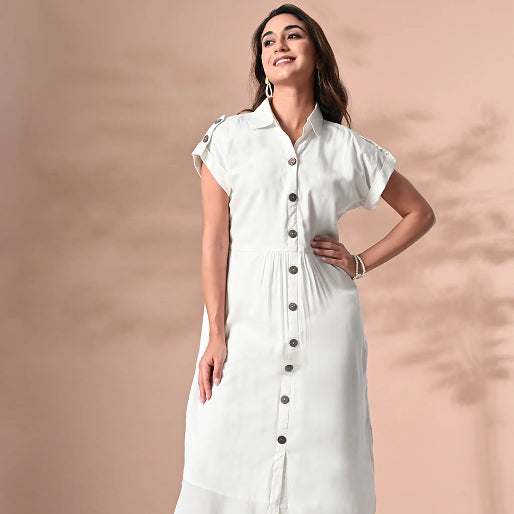 Woman wearing a white dress with buttons against a beige background